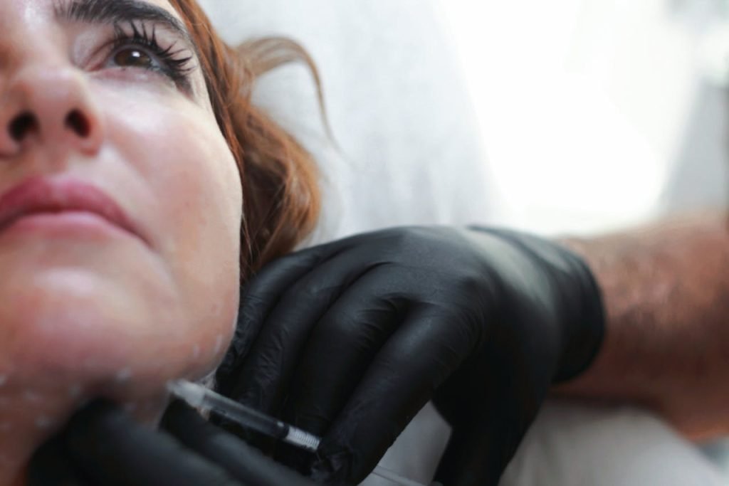 Woman getting botox shot to jawline.