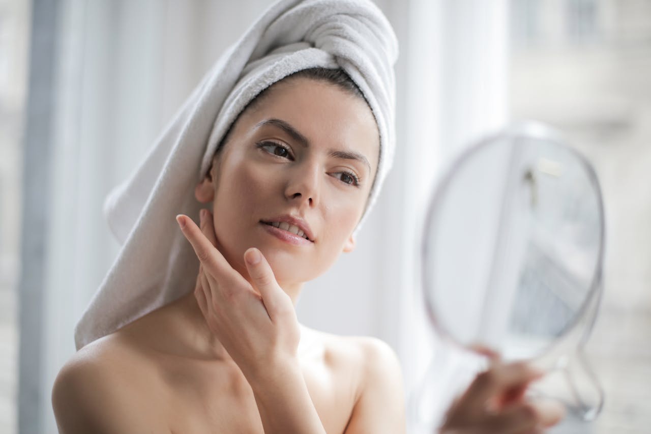 A beautiful woman looking in the mirror wondering how long do fillers last?