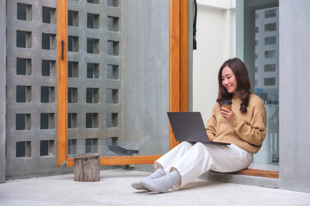 An attractive woman working on a laptop outside.